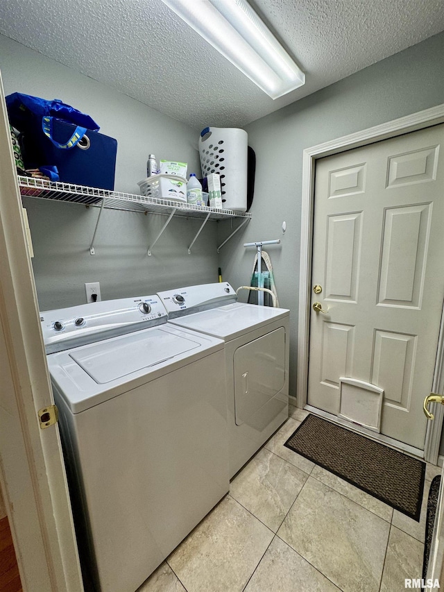 laundry area featuring washer and dryer, a textured ceiling, and light tile patterned floors