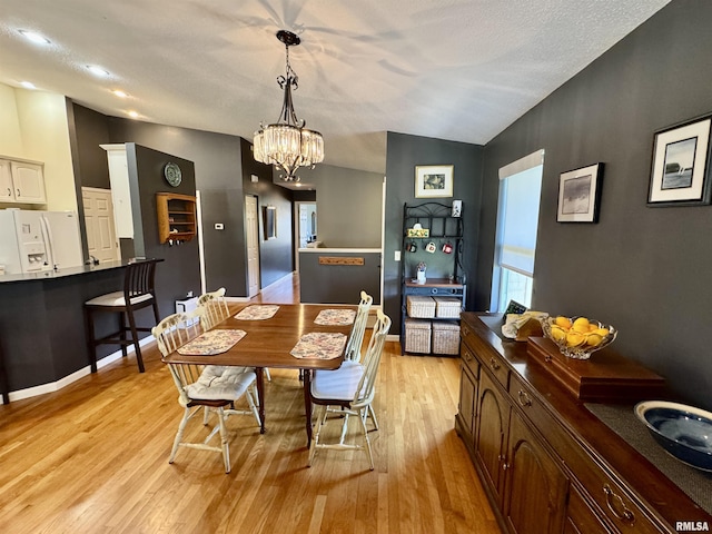 dining room with light wood-style flooring, a chandelier, and baseboards