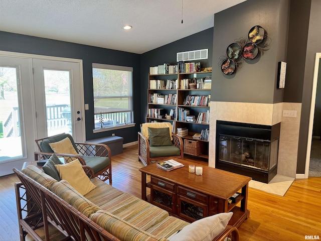 living area featuring healthy amount of natural light, wood finished floors, vaulted ceiling, a textured ceiling, and recessed lighting