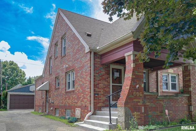 606 W Maywood Ave, Peoria, IL 61604 - view of front facade featuring brick siding, a shingled roof, a garage, an outdoor structure, and entry steps