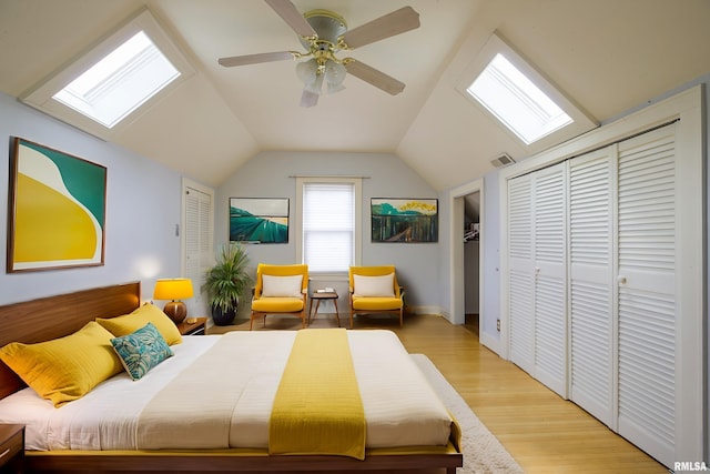 606 W Maywood Ave, Peoria, IL 61604 - bedroom featuring a skylight, lofted ceiling, light wood-style floors, ceiling fan, and two closets