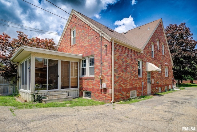 606 W Maywood Ave, Peoria, IL 61604 - view of side of home with a sunroom, brick siding, entry steps, and a shingled roof