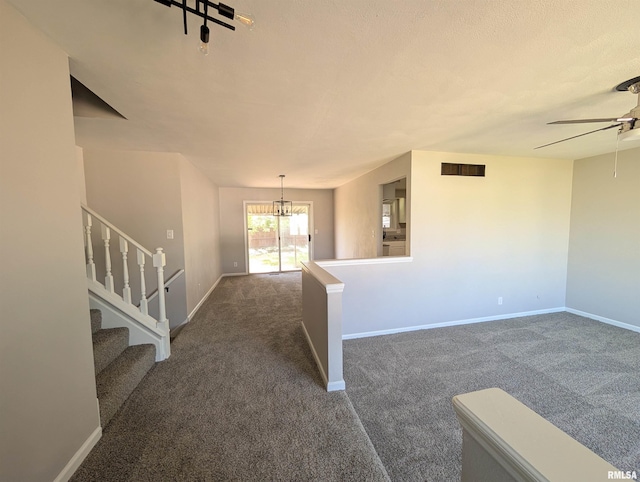carpeted entrance foyer with a ceiling fan, baseboards, a chandelier, and stairs