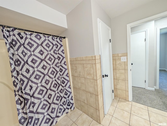 full bathroom featuring tile walls, tile patterned flooring, a shower with shower curtain, and a wainscoted wall