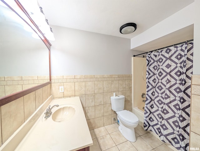 full bathroom with tile walls, tile patterned floors, toilet, a wainscoted wall, and shower / bath combo with shower curtain