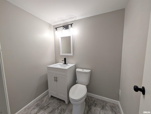 bathroom with baseboards, toilet, vanity, and marble look tile flooring