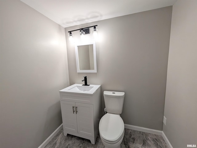half bathroom with baseboards, toilet, vanity, and marble finish floors