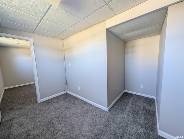 empty room with carpet flooring, baseboards, and a drop ceiling