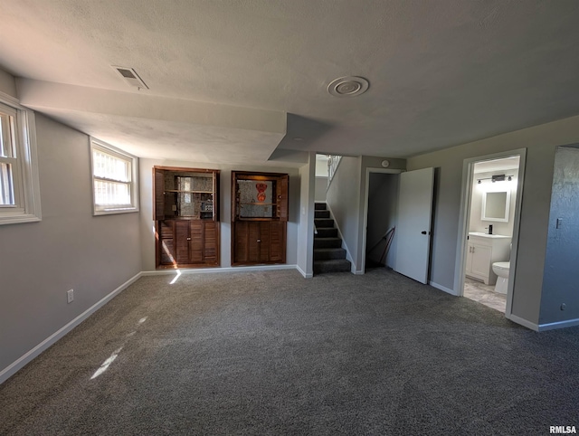 unfurnished living room with stairs, carpet floors, and baseboards