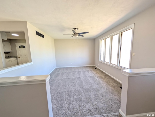 spare room featuring ceiling fan, light carpet, and baseboards