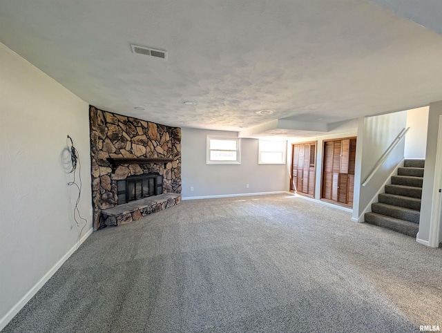 unfurnished living room with stairs, baseboards, a fireplace, and carpet floors