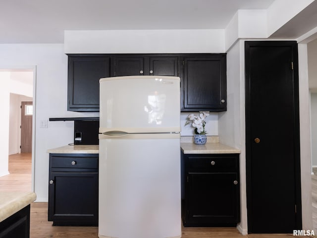 106 N 5th St, Dunlap, IL 61525 - kitchen featuring freestanding refrigerator, light wood finished floors, dark cabinets, and light countertops