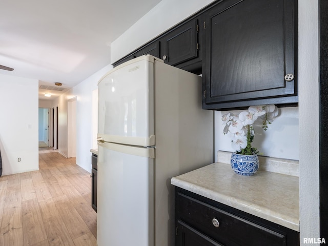 106 N 5th St, Dunlap, IL 61525 - kitchen with freestanding refrigerator, dark cabinetry, light wood-style flooring, and light countertops