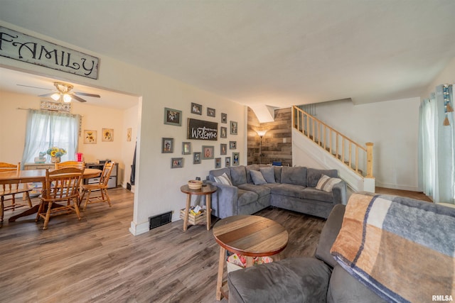 living area with stairs, wood finished floors, ceiling fan, and baseboards