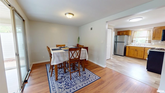 dining space with light wood-style flooring and baseboards
