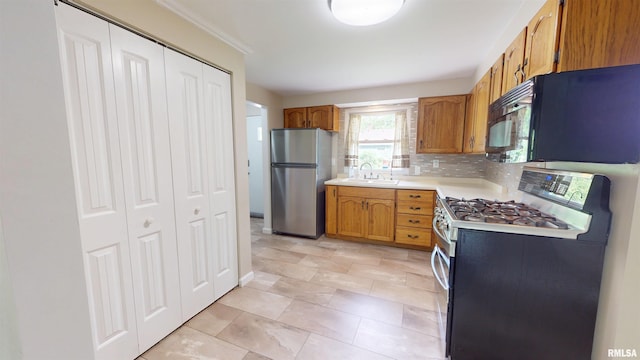 kitchen with stainless steel appliances, light countertops, brown cabinets, a sink, and decorative backsplash