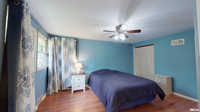 bedroom with wood finished floors, baseboards, a closet, and ceiling fan