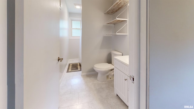 bathroom featuring toilet, tile patterned floors, vanity, and baseboards
