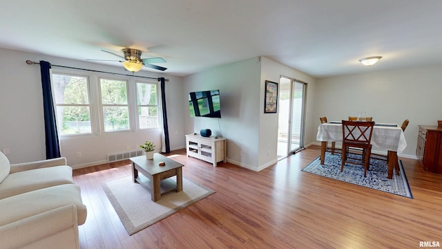 living area featuring healthy amount of natural light, wood finished floors, a ceiling fan, and baseboards
