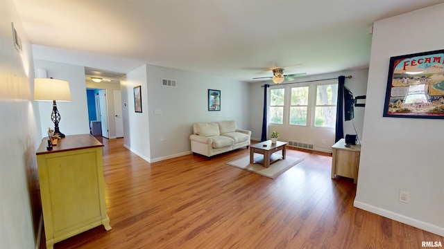 living room with light wood-type flooring, ceiling fan, and baseboards