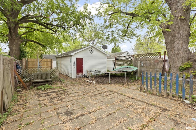 910 W Virginia Ave, Peoria, IL 61604 - view of patio featuring a storage shed, a fenced backyard, a trampoline, and an outbuilding