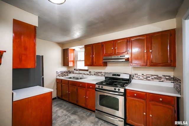 kitchen featuring stainless steel range with gas stovetop, a sink, under cabinet range hood, and light countertops