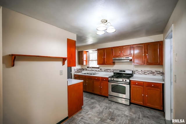 kitchen with stainless steel range with gas stovetop, a sink, light countertops, and under cabinet range hood
