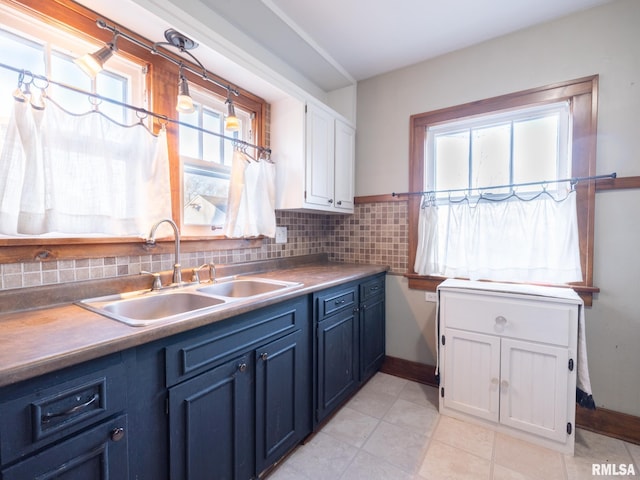kitchen featuring a sink, blue cabinetry, white cabinets, and light tile patterned floors
