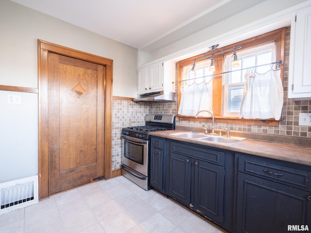 kitchen featuring gas range, a sink, under cabinet range hood, white cabinetry, and blue cabinets