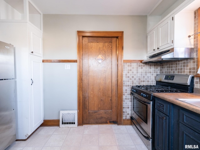 kitchen featuring stainless steel appliances, blue cabinetry, white cabinetry, under cabinet range hood, and decorative backsplash