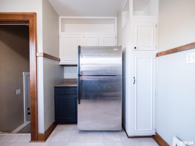kitchen with freestanding refrigerator, white cabinets, baseboards, and a baseboard heating unit