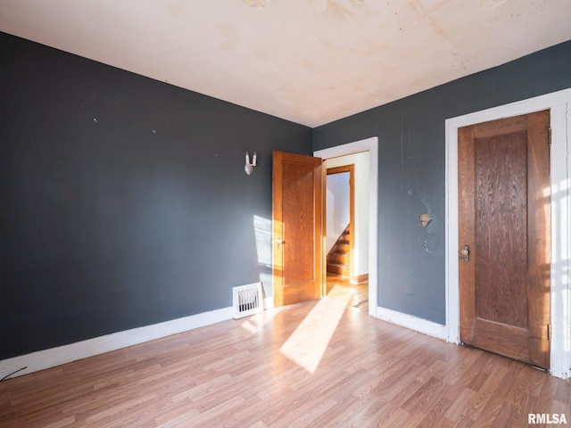 spare room with light wood-style flooring, baseboards, and stairway