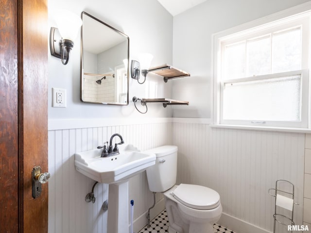 bathroom with a wainscoted wall, toilet, and tile patterned floors