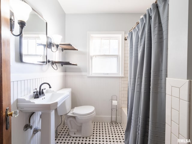 bathroom with wainscoting, toilet, tile patterned floors, and shower / bathtub combination with curtain