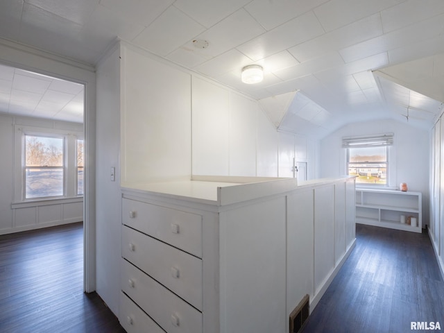 hallway featuring dark wood-style flooring, lofted ceiling, and a decorative wall