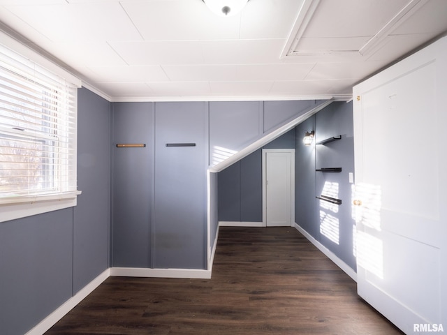 additional living space with dark wood finished floors and baseboards