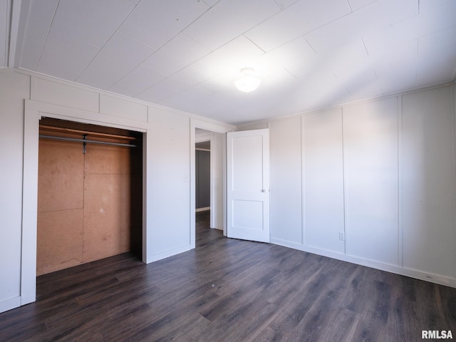 unfurnished bedroom with dark wood-type flooring, a decorative wall, and a closet