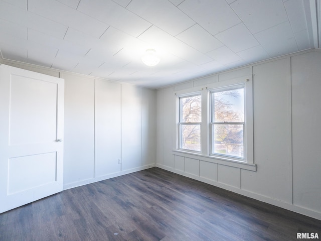 unfurnished bedroom featuring dark wood finished floors and a decorative wall