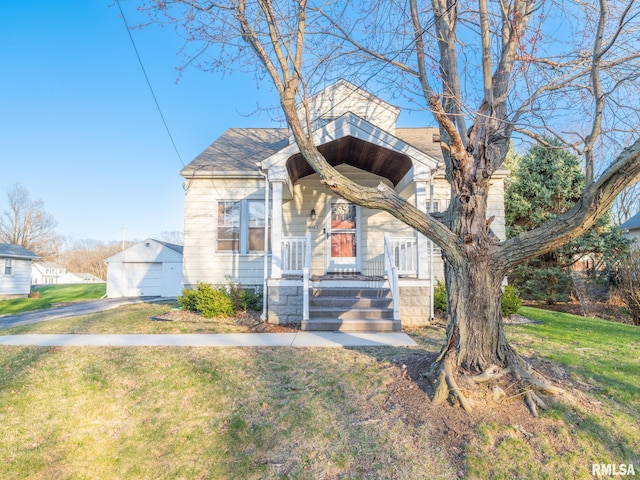 view of front of property featuring an outdoor structure, a front yard, roof with shingles, a detached garage, and covered porch