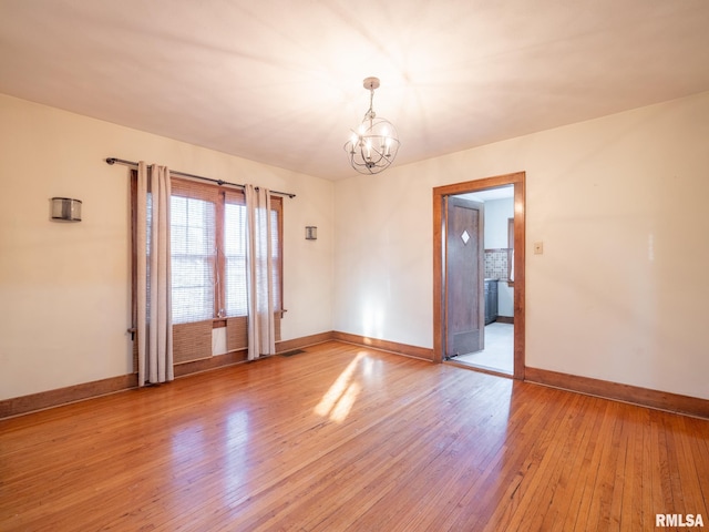 unfurnished room featuring a chandelier, baseboards, and light wood-style floors