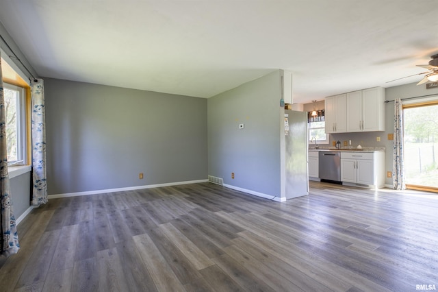 unfurnished living room featuring wood finished floors, plenty of natural light, and a sink