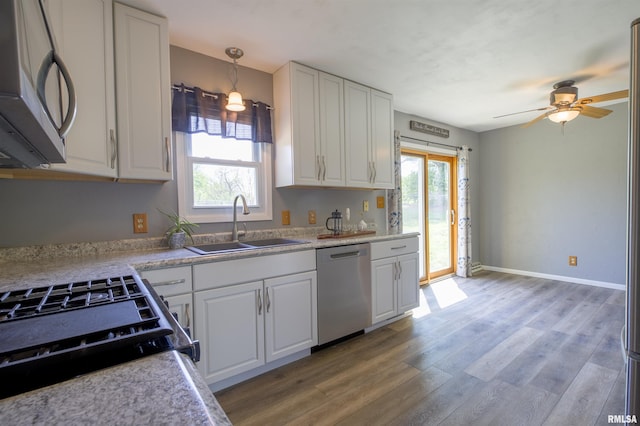 kitchen featuring stainless steel appliances, a sink, plenty of natural light, and light wood-style flooring