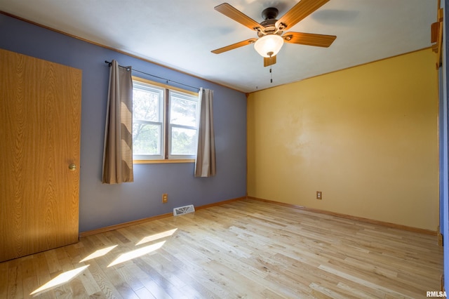 spare room featuring light wood-type flooring, ceiling fan, and baseboards