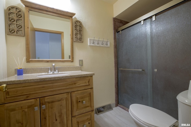 bathroom with toilet, a stall shower, and vanity