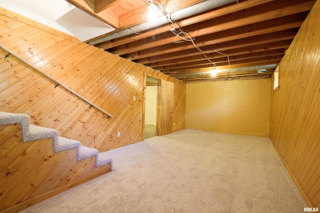 below grade area featuring carpet flooring, wood walls, and stairway