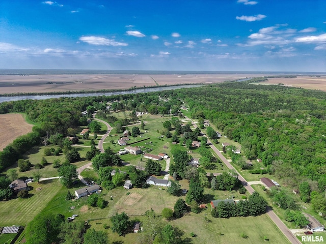 view of property location with a nearby body of water and a heavily wooded area