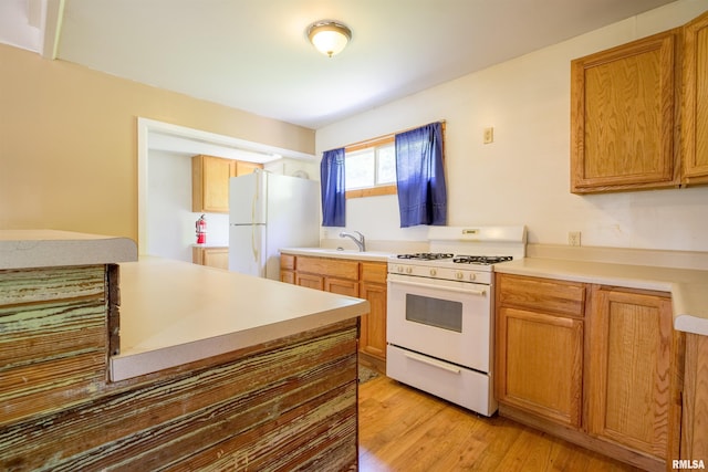 kitchen featuring white appliances, light wood-style floors, a sink, light countertops, and brown cabinets