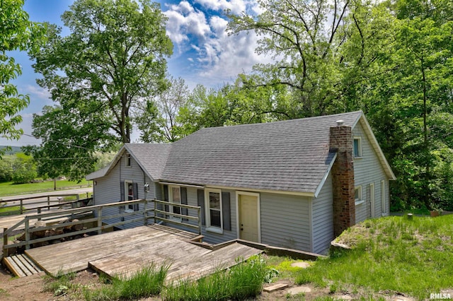 rear view of house featuring a shingled roof and a deck