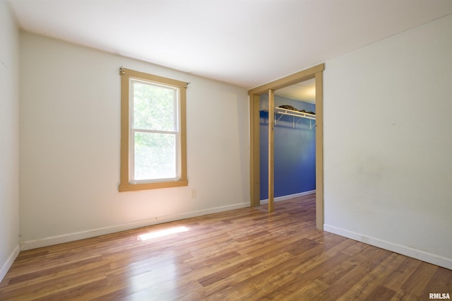 unfurnished bedroom with wood finished floors, a closet, and baseboards