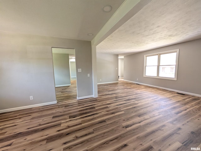 empty room featuring baseboards, wood finished floors, and a textured ceiling